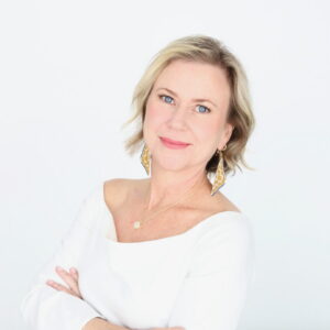 Johanna Leal, director ACJI, in a white shirt, stands in front of a white wall